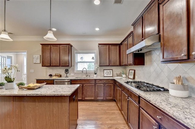 kitchen with sink, light stone counters, decorative light fixtures, stainless steel appliances, and light hardwood / wood-style floors