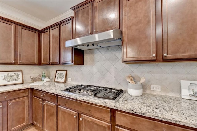 kitchen with light stone countertops, stainless steel gas cooktop, and backsplash