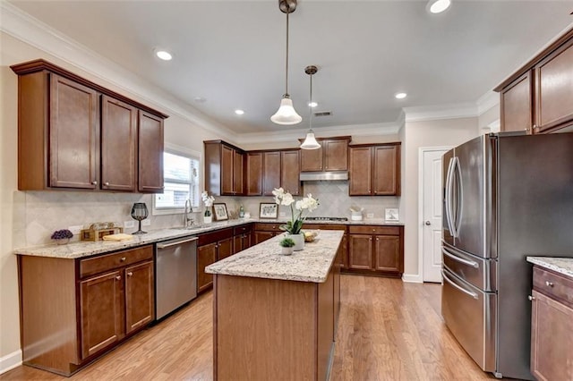 kitchen featuring light wood-type flooring, a kitchen island, pendant lighting, stainless steel appliances, and decorative backsplash