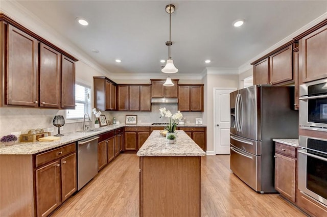 kitchen featuring pendant lighting, sink, appliances with stainless steel finishes, ornamental molding, and a kitchen island