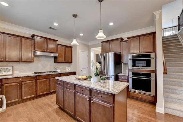 kitchen with decorative light fixtures, a center island, light hardwood / wood-style floors, stainless steel appliances, and light stone countertops