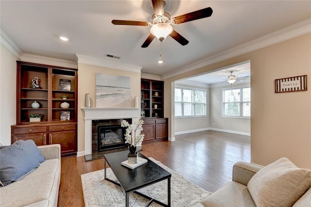 living room with hardwood / wood-style flooring, ornamental molding, and a premium fireplace