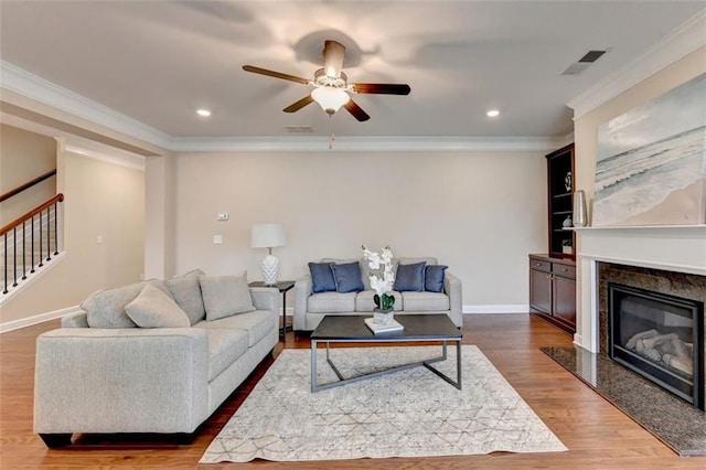 living room featuring dark wood-type flooring, ceiling fan, ornamental molding, and a high end fireplace