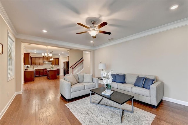 living room featuring crown molding, wood-type flooring, and ceiling fan with notable chandelier