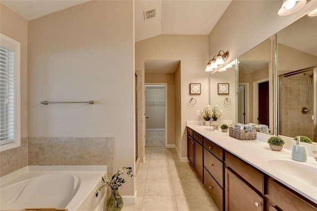 bathroom with vaulted ceiling, vanity, plus walk in shower, and tile patterned flooring