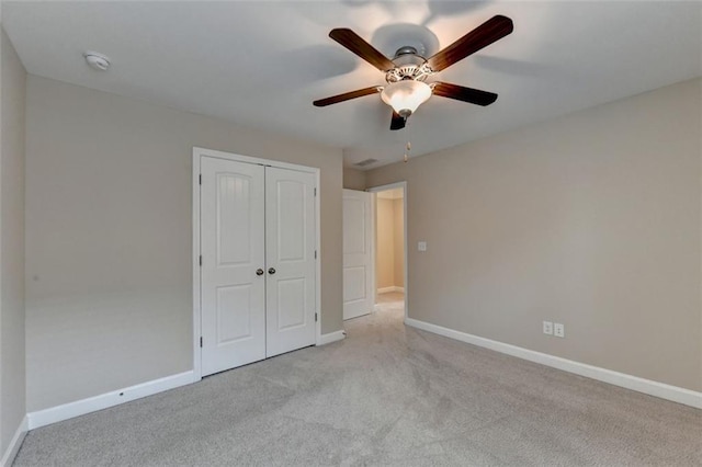 unfurnished bedroom featuring light carpet, a closet, and ceiling fan