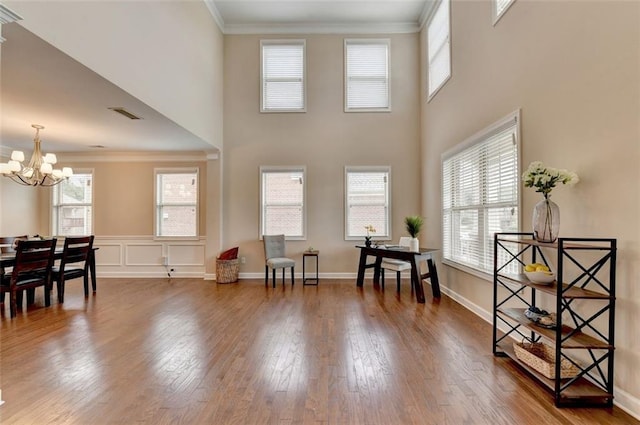 living area featuring crown molding, a notable chandelier, wood-type flooring, and plenty of natural light