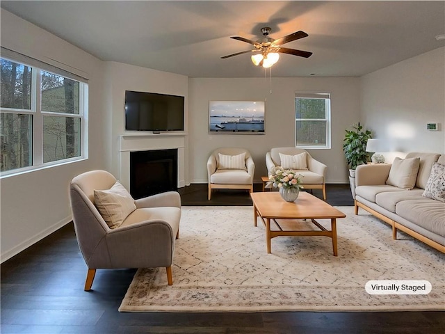 living room with baseboards, a ceiling fan, wood finished floors, and a fireplace