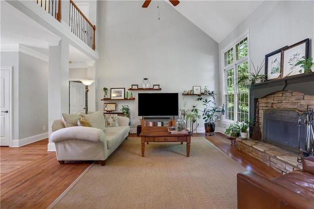 living room with a stone fireplace, a high ceiling, and light wood-type flooring