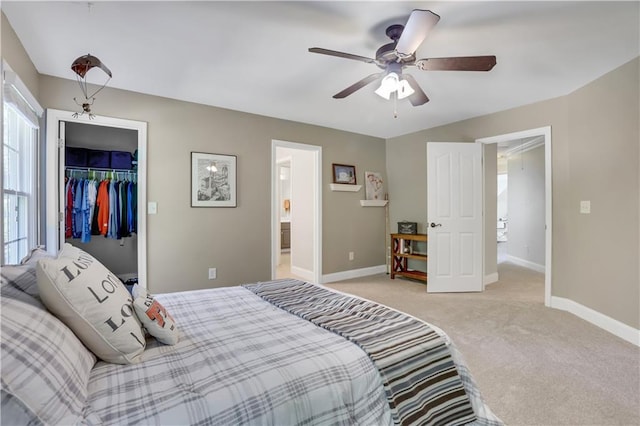 bedroom featuring ceiling fan, connected bathroom, light carpet, a walk in closet, and a closet