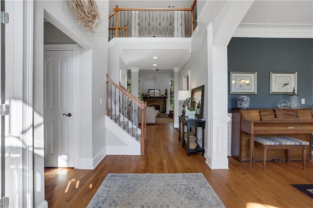 foyer featuring crown molding, a high ceiling, decorative columns, and hardwood / wood-style flooring