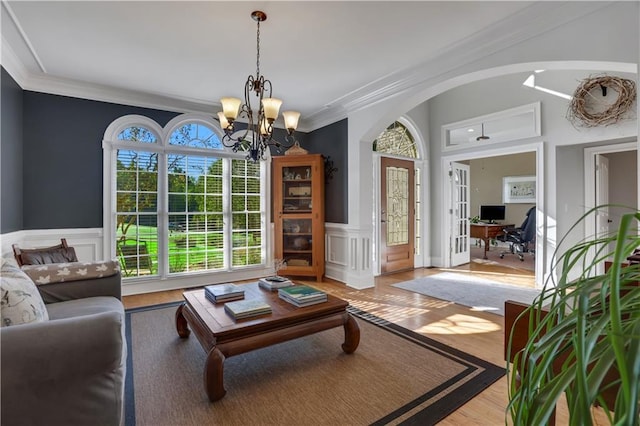 living room featuring crown molding, a chandelier, and light wood-type flooring