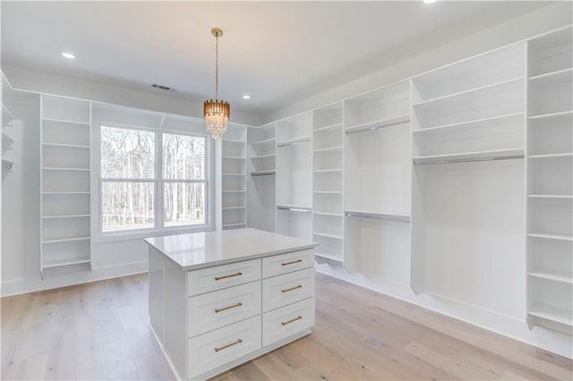 spacious closet featuring a chandelier and light wood-type flooring