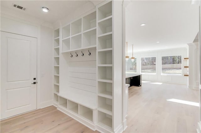 mudroom featuring built in shelves and light wood-type flooring