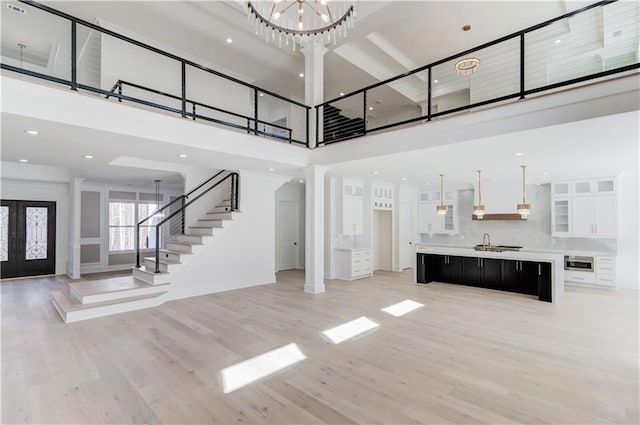 interior space featuring french doors, sink, an inviting chandelier, light hardwood / wood-style flooring, and a high ceiling