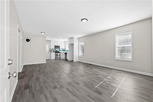 unfurnished living room featuring dark wood-style flooring and baseboards