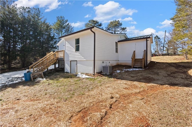 view of side of home with entry steps, metal roof, central AC unit, and a standing seam roof