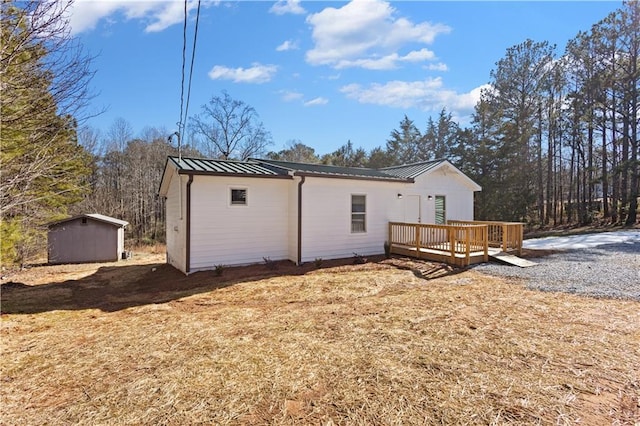 back of house with a storage shed, a standing seam roof, metal roof, an outdoor structure, and a wooden deck