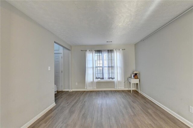 unfurnished room featuring a textured ceiling and light hardwood / wood-style flooring