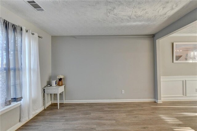 empty room featuring wood-type flooring and a textured ceiling