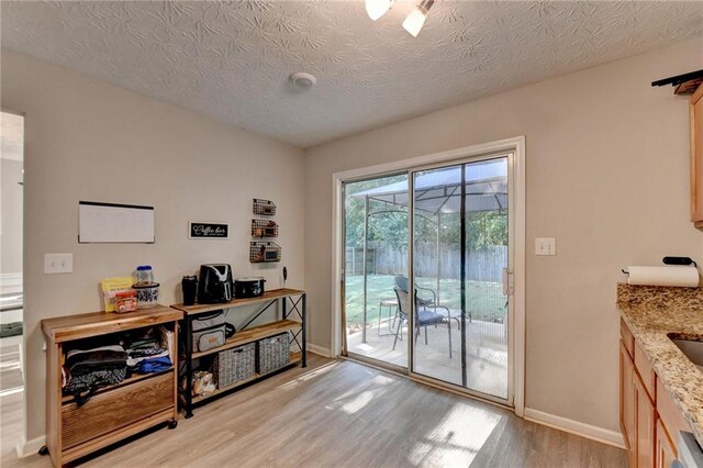 doorway to outside with a textured ceiling and light hardwood / wood-style flooring