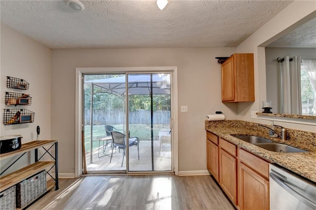 kitchen featuring a textured ceiling, dishwasher, sink, and plenty of natural light