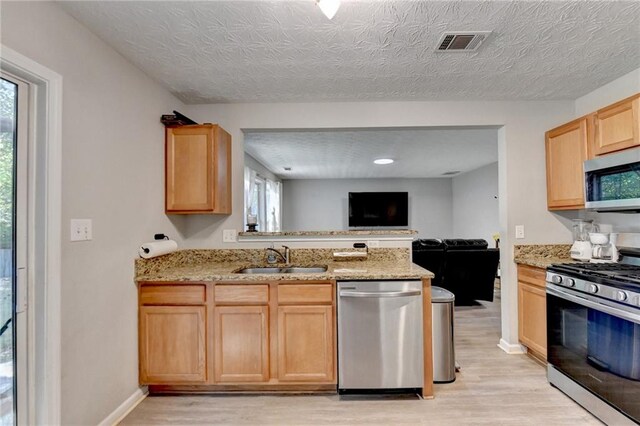 kitchen featuring light brown cabinets, appliances with stainless steel finishes, light wood-type flooring, and sink