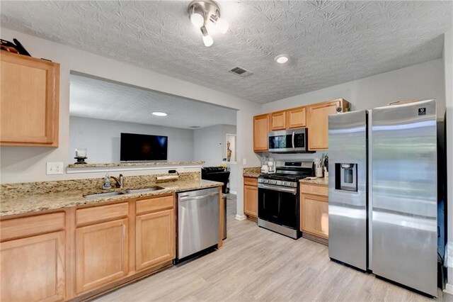 kitchen featuring stainless steel appliances, light brown cabinetry, and sink