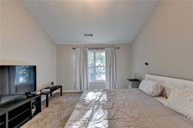 bedroom with a textured ceiling, lofted ceiling, and light colored carpet