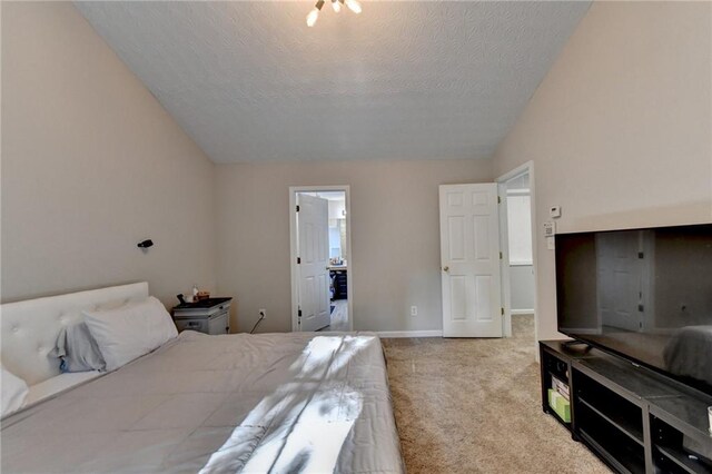 carpeted bedroom with lofted ceiling, a textured ceiling, and ensuite bath