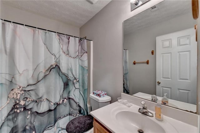 bathroom with a shower with shower curtain, a textured ceiling, vanity, and toilet