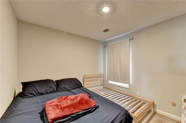 bedroom featuring a textured ceiling and light colored carpet