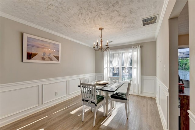 dining space featuring ornamental molding, a textured ceiling, a chandelier, and hardwood / wood-style floors