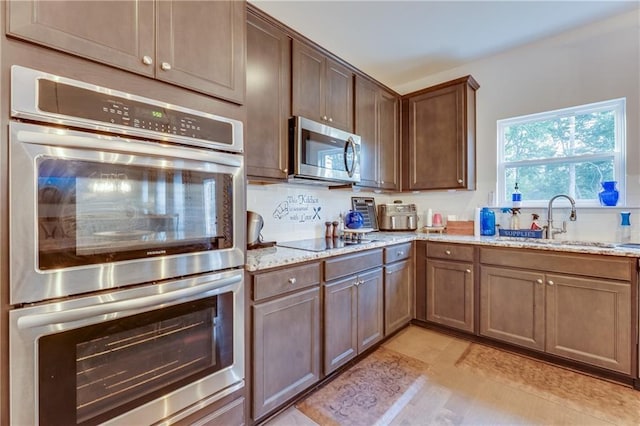 kitchen featuring light stone countertops, appliances with stainless steel finishes, and sink