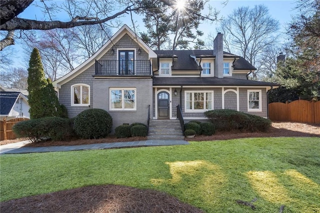 view of front of house featuring a front lawn, a balcony, and fence