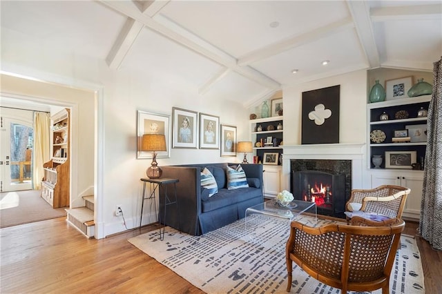 living area with lofted ceiling with beams, built in features, light wood-style flooring, and a high end fireplace