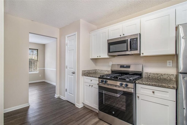 kitchen with baseboards, stone counters, stainless steel appliances, dark wood-type flooring, and white cabinets