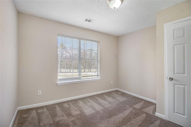 carpeted spare room with baseboards, visible vents, and a textured ceiling