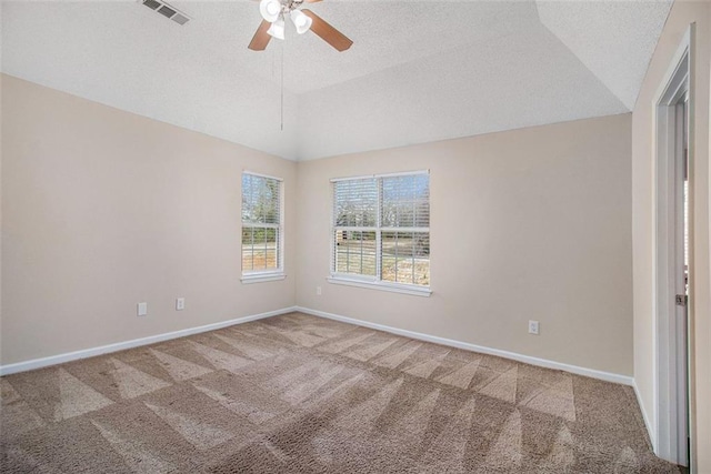 carpeted spare room with visible vents, ceiling fan, baseboards, and vaulted ceiling