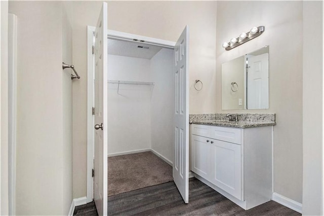 bathroom featuring vanity, a spacious closet, wood finished floors, and baseboards