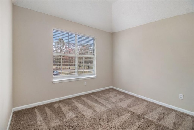 spare room with vaulted ceiling, baseboards, and carpet floors