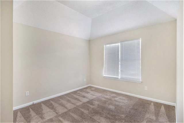 carpeted spare room featuring vaulted ceiling, baseboards, and a textured ceiling