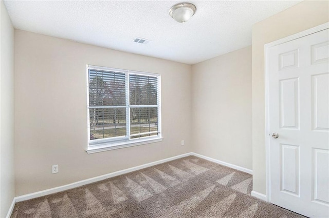 spare room featuring visible vents, baseboards, carpet, and a textured ceiling