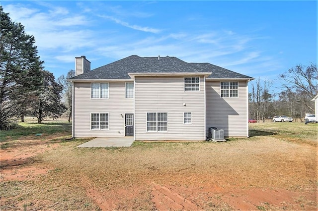 back of property with a yard, a patio area, and a chimney