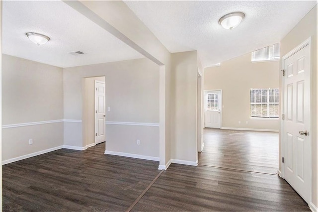 empty room featuring dark wood finished floors, visible vents, a textured ceiling, and baseboards