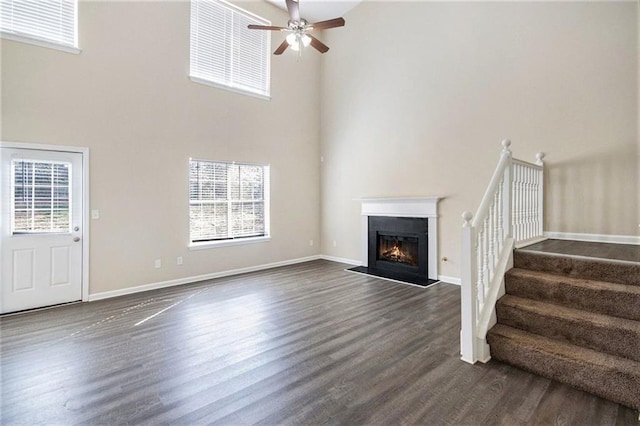 unfurnished living room with a ceiling fan, dark wood-style flooring, and a healthy amount of sunlight