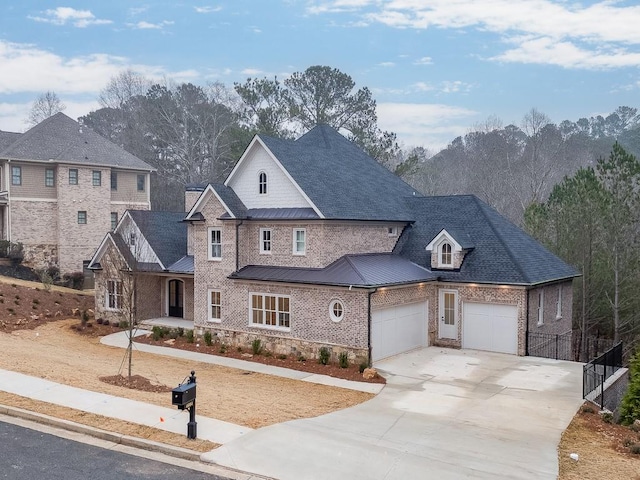 view of front of house with driveway, metal roof, an attached garage, a standing seam roof, and brick siding