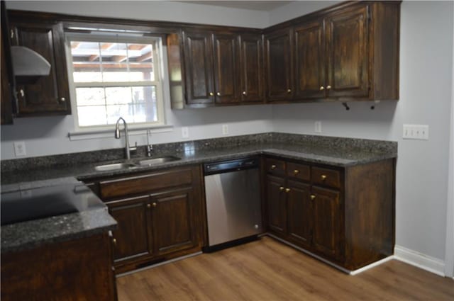 kitchen with sink, wood-type flooring, dark brown cabinets, dark stone countertops, and stainless steel dishwasher