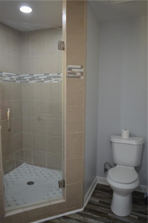 bathroom featuring hardwood / wood-style flooring, toilet, and an enclosed shower