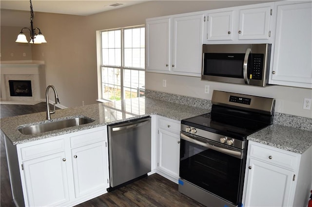 253 Woodland Way, Canton, GA 30114 - kitchen featuring white cabinets, a peninsula, appliances with stainless steel finishes, a sink, and an inviting chandelier